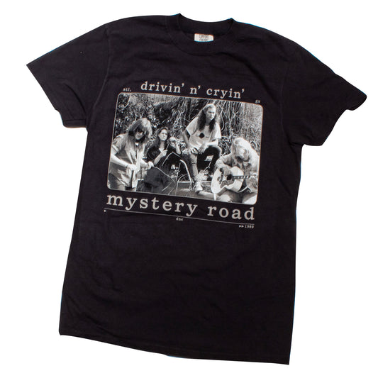 A black short-sleeve graphic t-shirt featuring a vintage-style black and white print of the band Mystery Road on the front, with the text 'drivin' n' cryin'' above and 'mystery road' below.